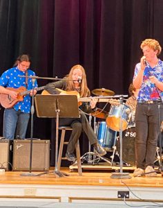 Students and teacher singing on stage together.