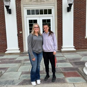 Two teens stand in front of Middleburgh High School