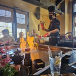 Student and adult at hibachi table with open flame and chef.