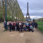 Students stand in group in front of Eiffel Tower.
