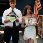 Students holding decorated graduation caps.