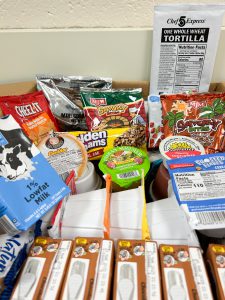 Box packed with non-perishable food items like cereal, nut butter and crackers.