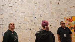 Students look at walls covered with paper notes.