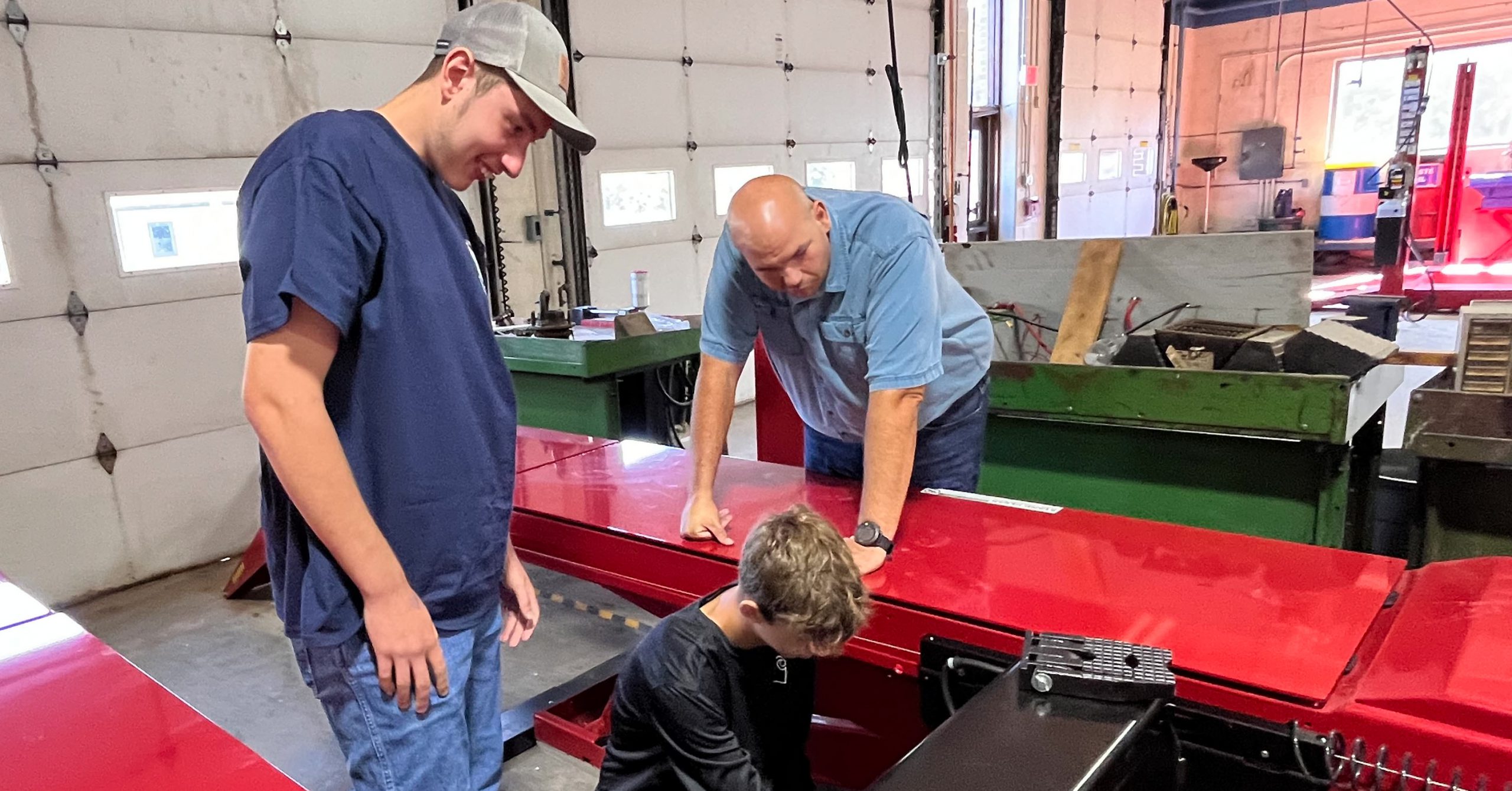 One student and one teacher look on as student work on auto lift.