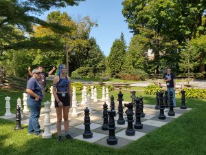 Several teens on giant outdoor chess board.