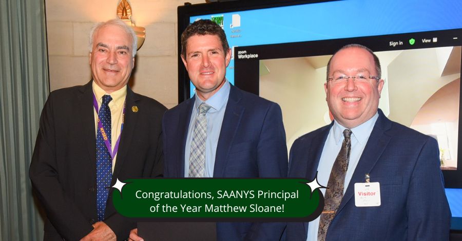 Three men, including Principal Matthew Sloane and Superintendent Mark Place stand together. They are dressed in business attire.