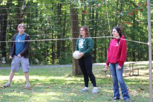 Three members of the Class of 2025 playing volleyball.