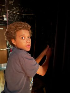 Student adjusts stage curtains.