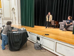 One student directs two students acting on stage.