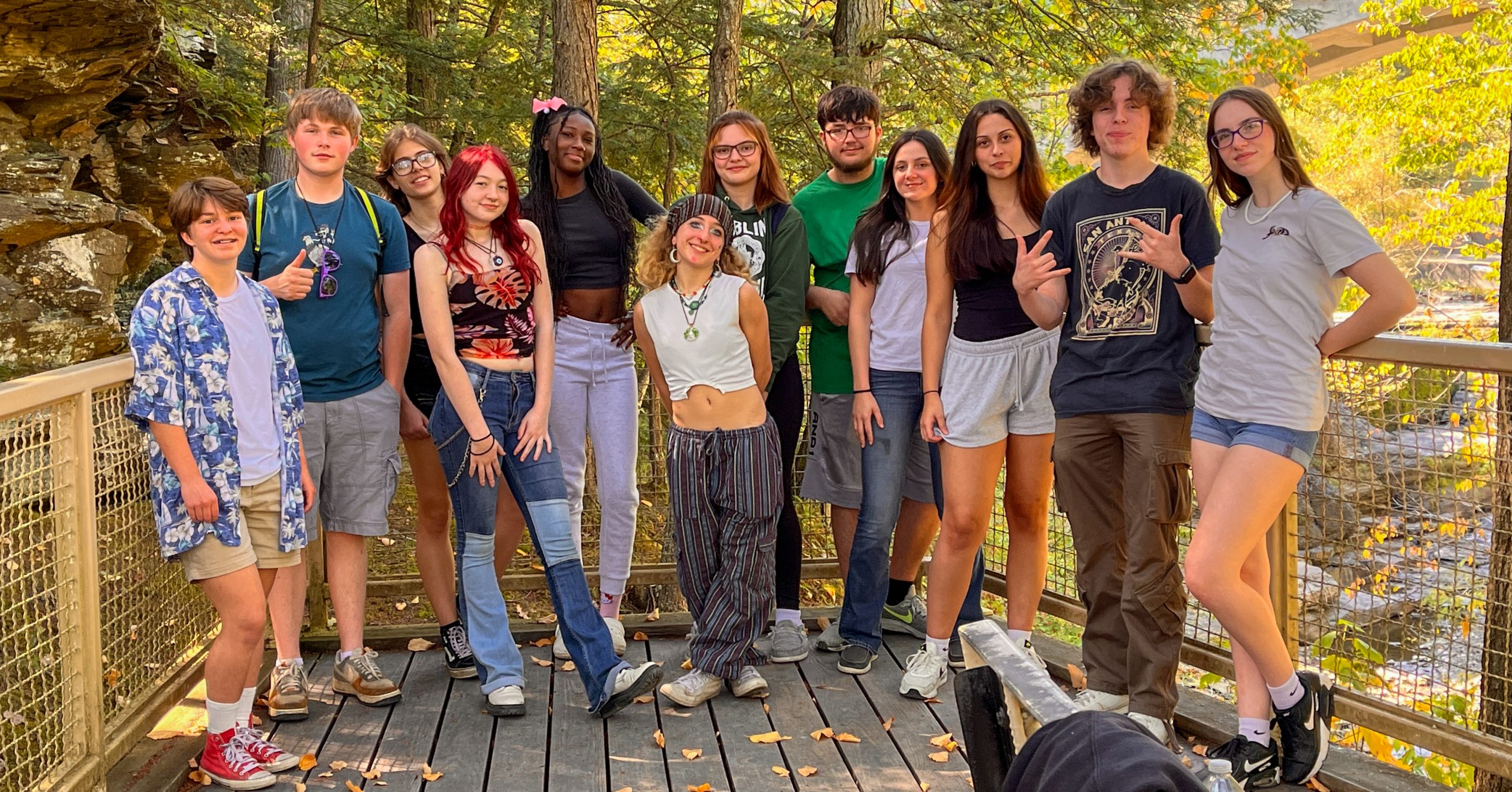 Twelve seniors stand together on a bridge in early autumn. 