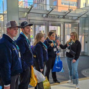 Four students wearing matching Middleburgh FFA jackets are interview in convention lobby.