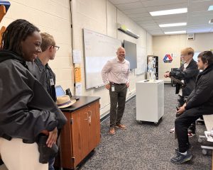 Four students listen to an adult speaker.