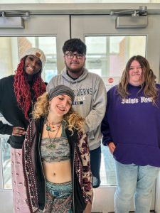 Four students stand in front of doors.
