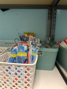 Toothbrushes and other personal care items in bins on shelves.