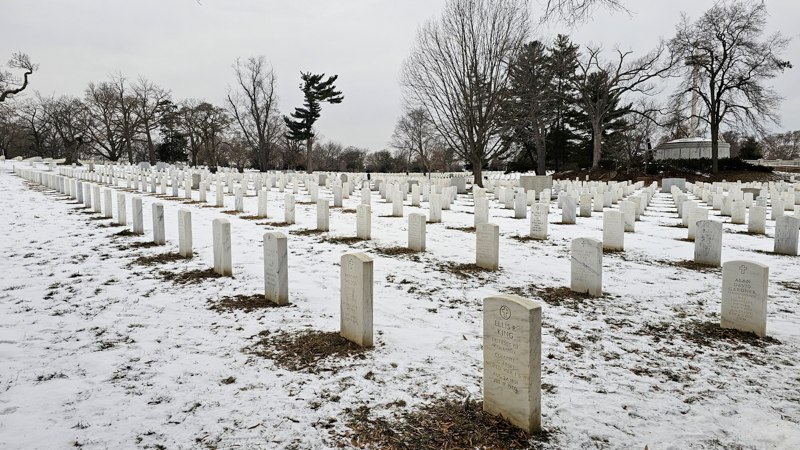 Tombstones at Arlington National Cemetery covered in light snow.