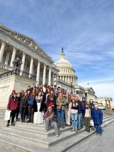 Students and teachers stand on steps of U.S. Capitol.