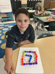 Elementary student sits at table with project in front of him.