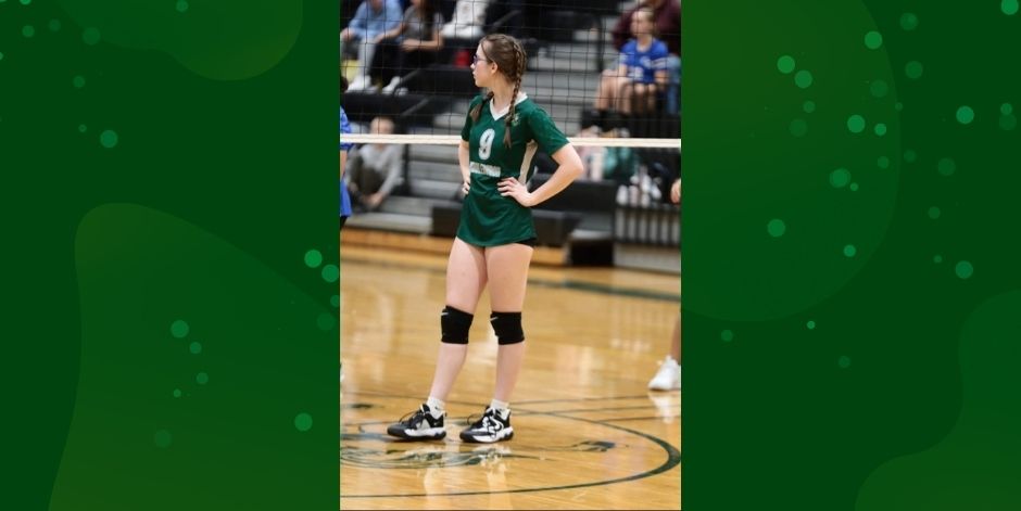 Student stands on volleyball court.