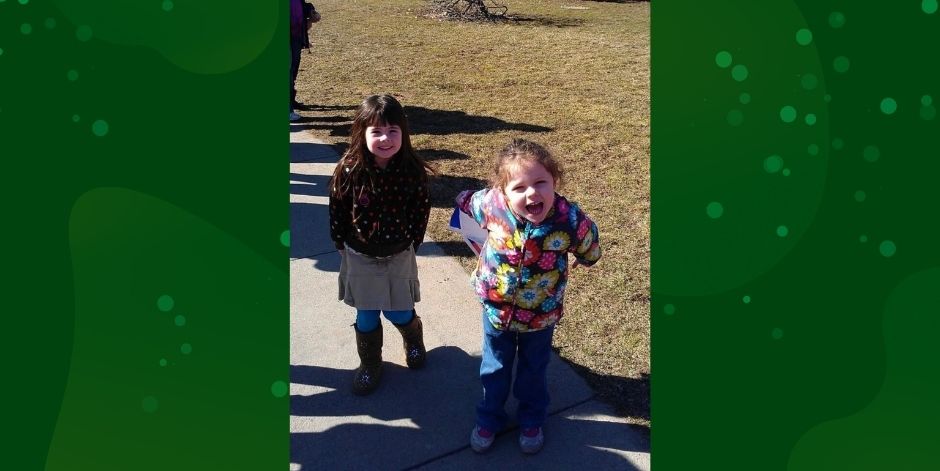 Two young children stand on sidewalk.