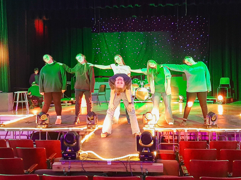 Five students on stage. Teen in foreground in doing a backbend.